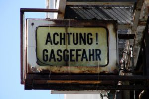 Altes Schild mit in verblichenem Gelb mit schwarzer ufschrift "Achtung! Gasgefahr