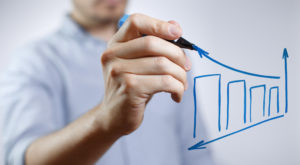 Gaspreise sind schwer prognostizierbar Mann in blauem Hemd der eine steigende Kurve zeichnet