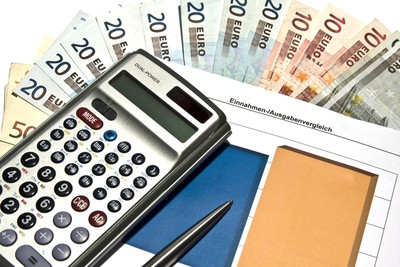 Taschenrchner mit einem Datenblatt darunter sowie Geldscheinen von 5 bis 50 €