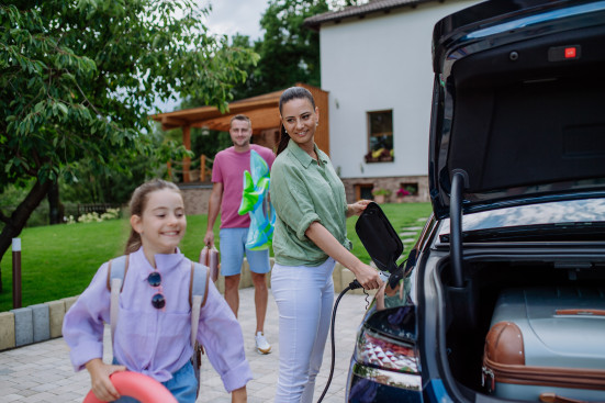 Familie packt das Elektroauto für den Sommerurlaub