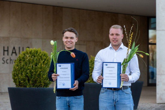 Die zwei Facharbeiter präsentieren ihr Zeugnis.