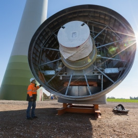 Mann vor dem Generator einer Windkraftanlage