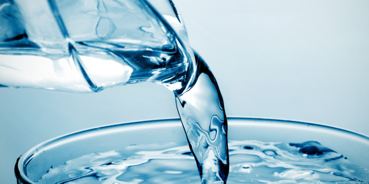 Wasser aus Glaskanne in ein Glas gießen