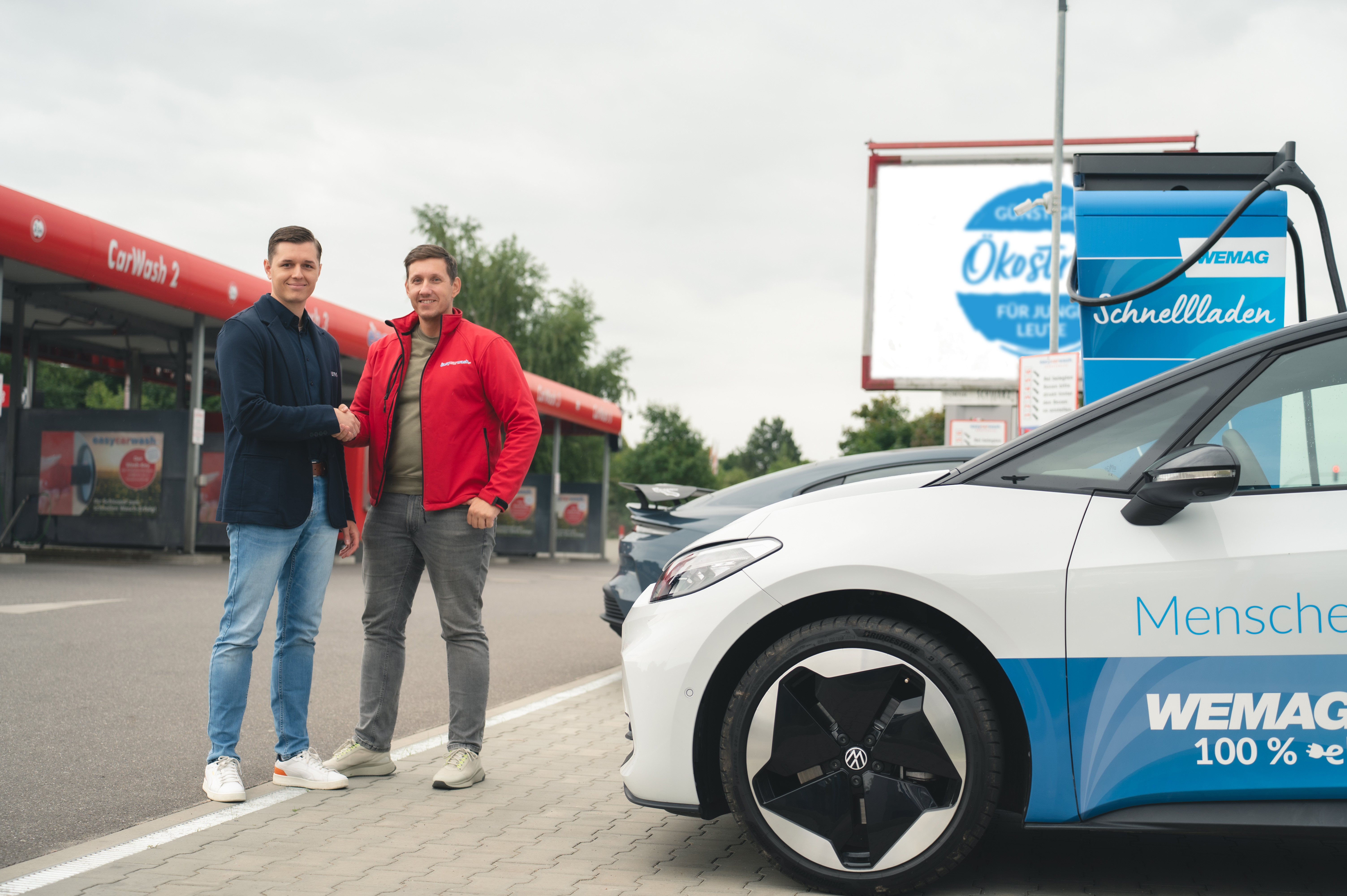 Felix Plückhahn, WEMAG Projektleiter, und Henrik Mernitz, Geschäftsführer von EasyCarWash, posieren vor der Schnelladesäule. 