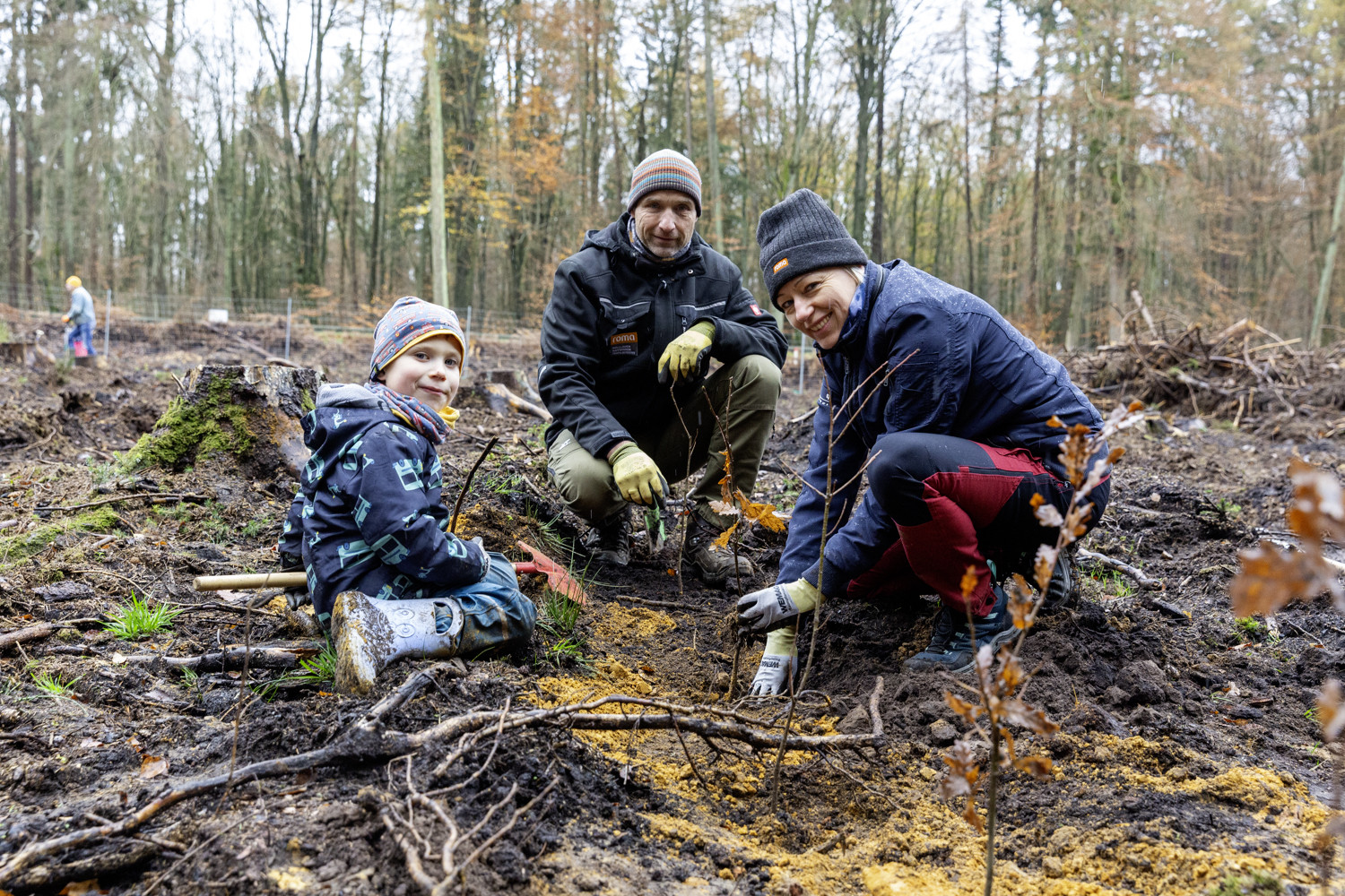 Zwei Eltern pflanzen einen Baum mit ihrem Sohn.