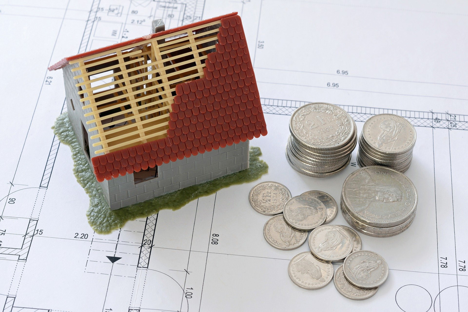 Wie hoch sind die Gaskosten und der Gasverbrauch in einem Einfamilienhaus? Haus im Miniaturformat mit Geldstücken daneben