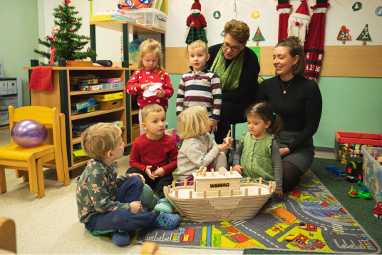 Kinder in der Kita „Sonnenschein“ spielen mit einem Holzschiff der WEMAG während der Weihnachtsaktion.